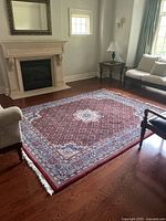 Rug laid on hardwood floor near fireplace, full view showing pattern and fringe.