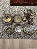 Top view of vintage silver tea set and assorted silver bowls displayed on leopard print cloth.