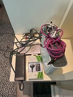 Photo showing white Xbox 360 console with coiled cables on top, black power supply brick, and Play & Charge Kit box on a white surface.