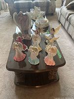 Angel figurines and glass votive holders arranged on a coffee table, showing variety in sizes and colors.