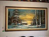 Full view of the large framed painting showing a snowy forest scene with a lake and sunset sky.