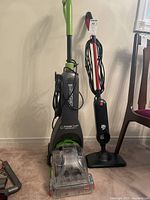 Full view of both vacuum cleaners side by side showing Bissell Powerclean Turbobrush Pet with dirt receptacle and Dirt Devil vacuum.