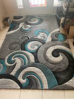 Full view of rectangular Bristol area rug displaying swirling abstract pattern in gray, black, teal, and white colors on a thick pile surface.