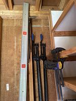 Photo showing two metal crank clamps approximately 79 inches long along with a 100-inch metal level with red bubble vials.