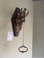 Front view showing the whole wood board with brass door knocker and hanging hammer chain.