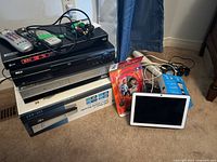 Wide shot showing LG Blu-ray player BD570C, RCA DVD player, LG DVD and VCR LVC-837 in box, headphones in packaging, remote controls and AV cords, Google Home device and white smart display on carpet floor.