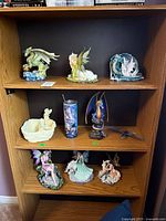 Full shelf showing 9 items including 6 figurines, 1 travel mug, and 1 candle holder across three shelves