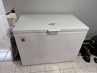 Front view of a white Amana chest freezer showing the brand logo and a sticker.