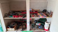 Wide view of vintage hand tools on shelves including files, clamps, and boxed Black & Decker jigsaw.