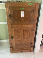 Front view of vintage wooden ice box showing two storage compartments and metal hinges.