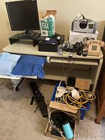 Full view of the lot on a rolling desk showing LG monitor, phones, docking system, boxes of cables.