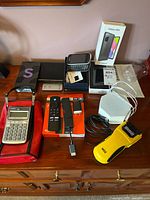 Full lot showing Samsung Galaxy A03s phone with box, phone cases, Amazon Fire TV Stick remote, calculator, stud finder and speaker.