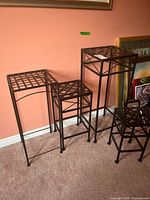 Four metal plant stands grouped together. Three stands are nesting, one is mismatched. Lattice tops visible. Shows general size and style.