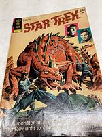 Front cover showing Star Trek cast with a large spiked dinosaur-like monster under attack scene.