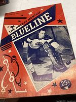Front cover of The Hockey Monthly Blueline magazine December 1954 featuring a hockey goalie in front of net with red and blue graphic elements