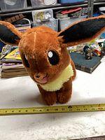 Front view of Pokémon Eevee plush toy showing facial features and size approximately 11 inches.
