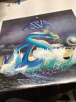 Front of the Asia vinyl album cover featuring a blue dragon or sea serpent emerging from ocean waves with a pearl or orb and band logo.