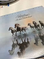 Front cover of Bob Seger & The Silver Bullet Band "Against The Wind" album featuring running horses against a blue sky background.