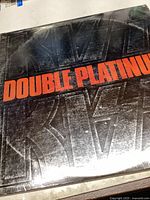 Close-up of scratched KISS Double Platinum album cover with embossed logo and red text.