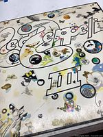 Front cover of the Led Zeppelin III album showing detailed colorful and whimsical artwork with circles, butterflies, and various images