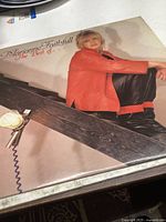 Front cover of Marianne Faithfull The Best Of vinyl record showing the artist sitting on a wooden plank.