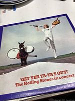Front cover of The Rolling Stones 'Get Yer Ya-Ya's Out!' vinyl album featuring a member jumping and a donkey with drums.