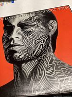 Record album cover with black and white tattooed face on red background