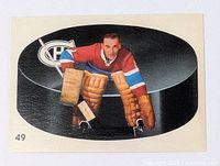 Full view of vintage hockey card showing Montreal Canadiens goalie in classic goalie pad stance with large puck background and Canadiens logo