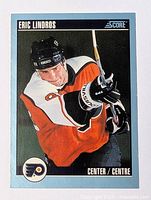 Front of 1992 Score Eric Lindros Philadelphia Flyers hockey card in orange uniform with hockey stick, mint condition.
