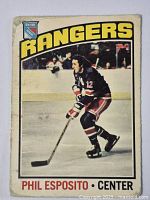 Front side of Phil Esposito hockey card showing him in New York Rangers uniform number 12 on ice.