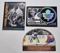 Three Curtis Joseph hockey cards displayed, two rectangular and one round half-moon, all with foil and holographic elements.
