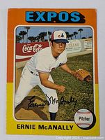 Front of the 1974 Ernie McAnally baseball card showing the player in Expos uniform on field, framed in orange with Expos and Coca-Cola branding visible.