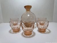 Front view showing the decanter with stopper centered and five surrounding tumblers.