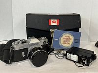 Front view of Canon camera, case, manual, flash, and accessories on display showing overall condition and contents.