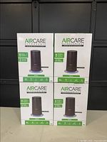 Front view of four boxed Aircare Mesa ultrasonic humidifiers stacked in two rows.