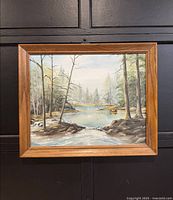 Front view of the framed fishing landscape painting showing a river surrounded by trees and a small boat on the water.