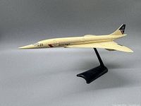 Side view of vintage off-white Concorde model airplane on black stand showing British Airways logo.