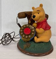 Front view of vintage Disney Winnie The Pooh Telemania rotary dial desk phone with handset and cord coiled to the side.