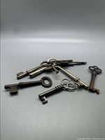 Lot of several early vintage skeleton keys and one key ring with multiple keys, arranged on a plain background.