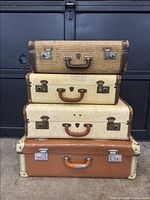 Stacked view of four vintage suitcases showing front faces, handles, locks, and color variations.