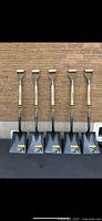 Five brand new Garant Pro Series landscape shovels standing upright against a brick wall, showing the full length and D-grip handles.