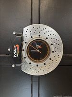 Front view of the wall clock shaped like a ventilated brake rotor and caliper, showing the MAX logo on the clock face and the caliper sticker.