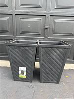 Photo of two black plastic planters with woven texture standing side by side, showing exterior condition and size.