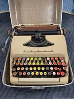 Top view of open typewriter in case showing keyboard layout and multicolor keys