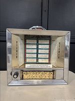 Front view of chrome Seeburg Wall-O-Matic tabletop jukebox selector showing glass display and push-button selection array.