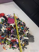 Pile of various colorful LEGO bricks with a measuring tape showing length