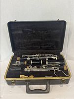 Full open case with disassembled clarinet pieces laid out inside including mouthpiece, barrel, upper joint, lower joint, and bell.