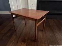 Full view of the teak side table showing its rectangular top and four legs.