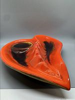 Front angled view showing the vibrant orange glaze with brown and black highlights and sculpted contours.