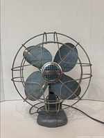 Front view of the vintage Electrohome Long Life table fan showing the four metal blades within protective wire cage and brand badge